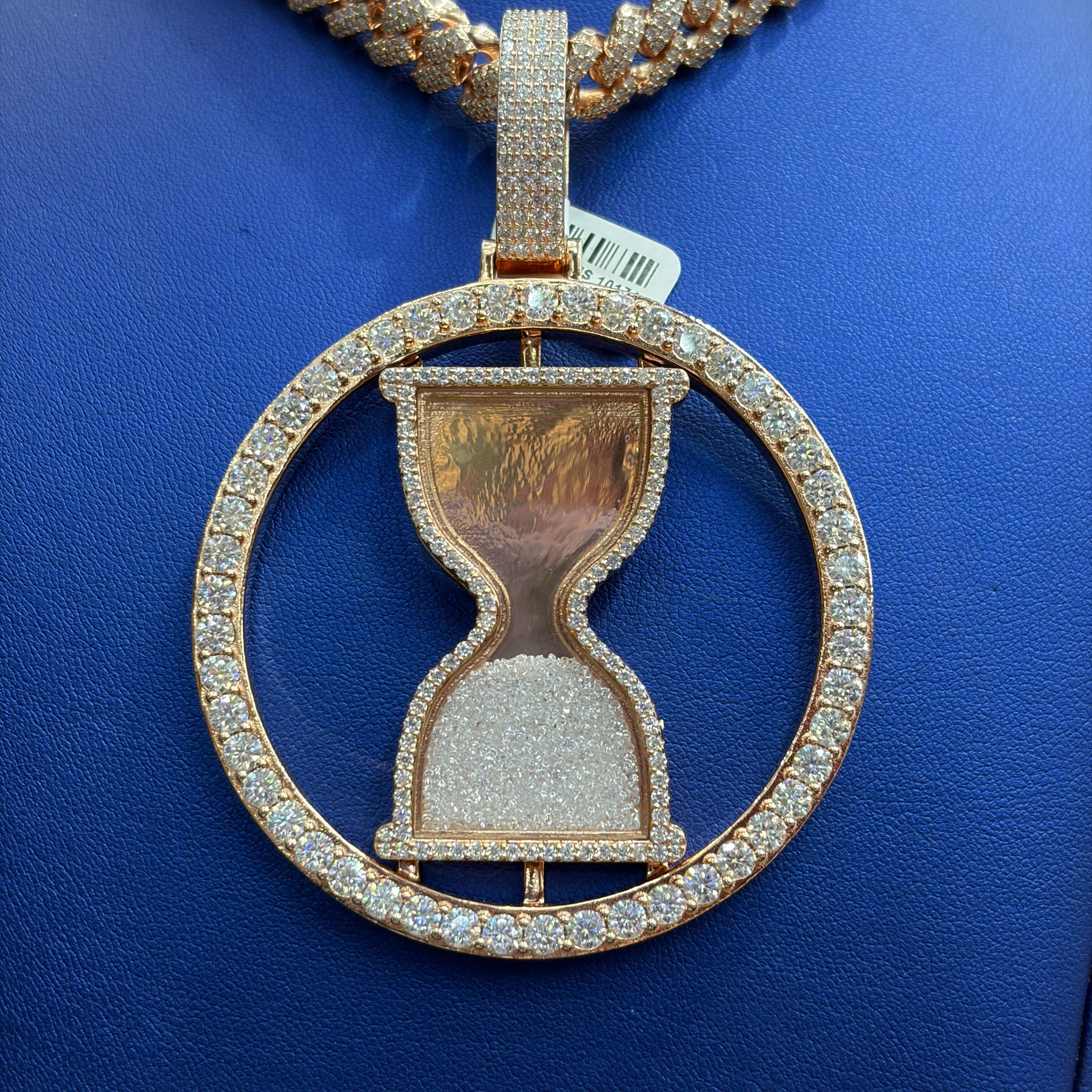 Rose gold hourglass pendant with diamonds on a blue background
